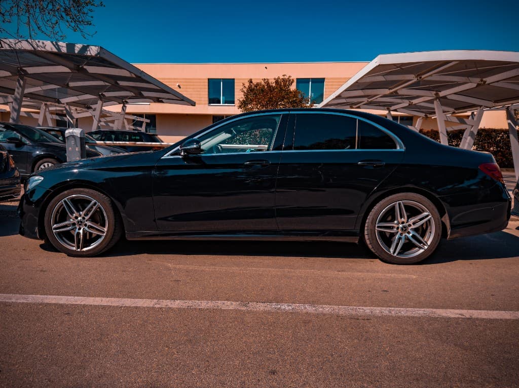 Black Mercedes-Benz S-Class side profile on an open lot under clear blue sky