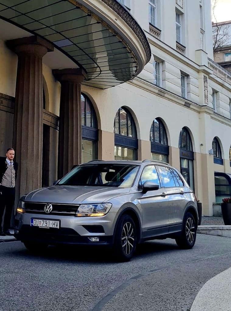 Silver Volkswagen Tiguan SUV outside a columned building with a glass canopy